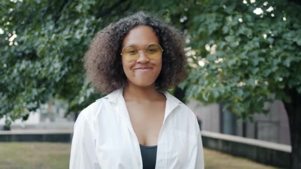 Portrait of beautiful African American woman in sunglasses smiling outdoors — стокове відео