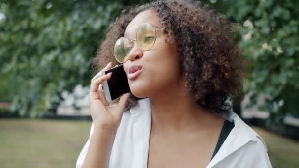 Cheerful Afro American lady chatting on mobile phone outdoors laughing — Stock Video