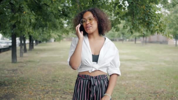 Heureux étudiant afro-américain bavarder sur téléphone portable dans le parc en été — Video