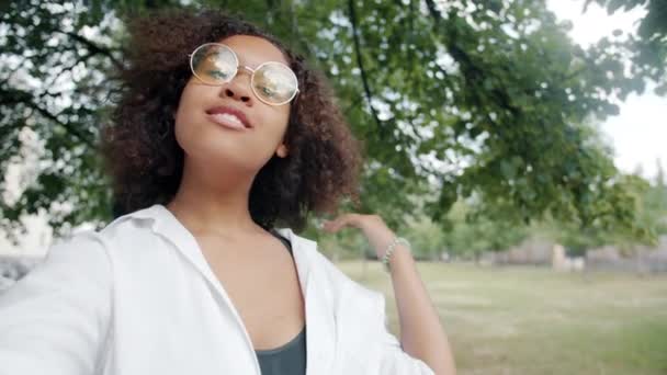 Bonito afro-americano menina tomando selfie ao ar livre mostrando dedais-up envio beijo — Vídeo de Stock