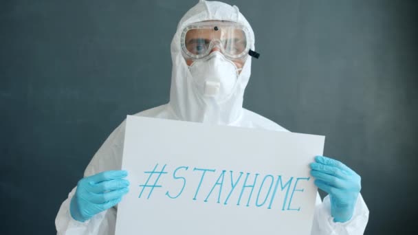 Portrait of Arab man in quarantine suit standing with stayhome banner on grey background — Stock Video