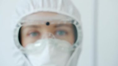 Güvenlik maskesi, takım elbise ve solunum cihazı takan ciddi bir kadın doktorun portresi.