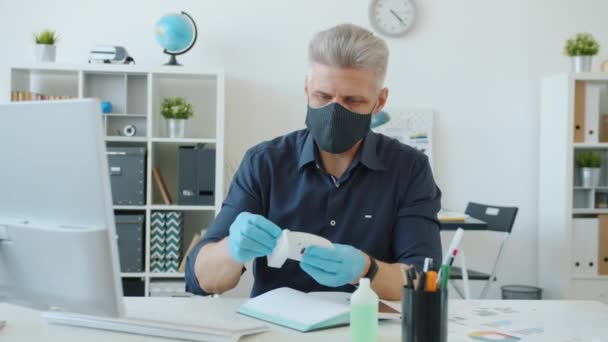 Trabalhador de escritório computador de limpeza úmida com higienizador de mãos no trabalho durante a pandemia — Vídeo de Stock