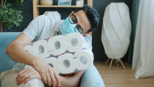 Maskeli çılgın Orta Doğulu adamın portresi. Evde uyurken tuvalet kağıdı ruloları sarılıyor. — Stok video