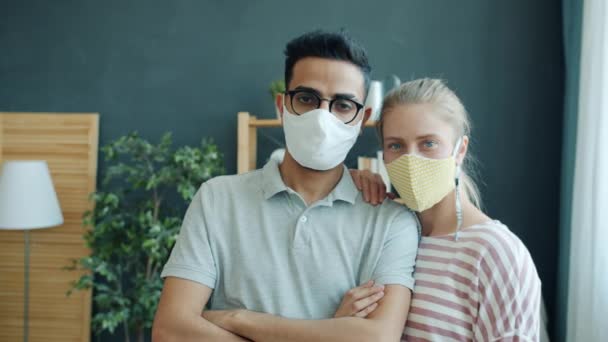 Portrait de jeune couple homme arabe et femme caucasienne portant des masques à la maison — Video