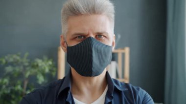 Evde el yapımı maske takan yetişkin bir adamın yakın plan portresi.