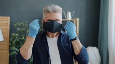 Ciddi bir adamın portresi. Kumaş takıyor, maske takıyor. Evdeki kameraya bakıyor.
