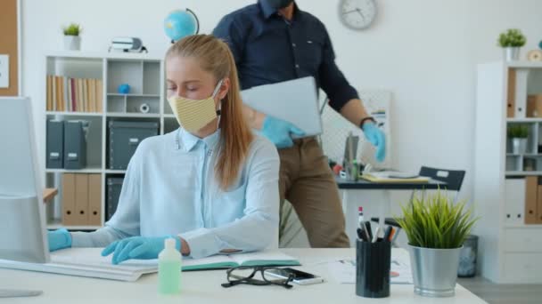 Mujer con mascarilla facial trabajando con computadora y luego despidiéndose de su colega en la oficina — Vídeos de Stock