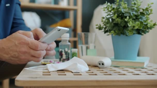 Gros plan des mains des hommes utilisant un smartphone pendant la pandémie de coronavirus à la maison — Video