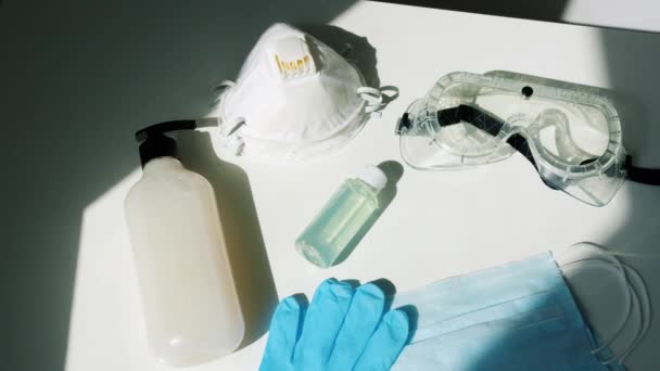 Vista de alto ângulo de higienizadores de mãos, máscaras faciais, óculos de proteção e respirador na mesa — Vídeo de Stock