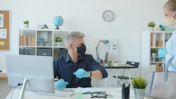 Mann und Frau in Gesichtsmasken Büroangestellte tun Ellbogen High-Five bei der Arbeit während der Pandemie — Stockvideo