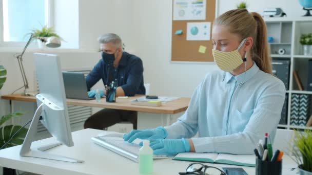 Деловые люди в масках и перчатках, работающие с компьютерами, печатающими в офисе — стоковое видео