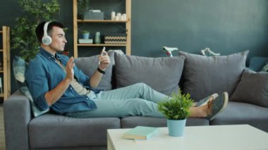 Tasasız genç adam akıllı telefonu tutuyor ve kulaklıkla içeride müzik dinliyor.