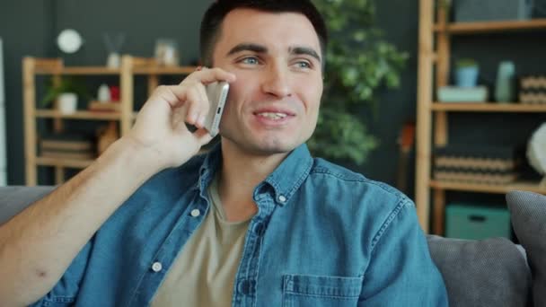 Повільний рух щасливого дорослого чоловіка, що розмовляє на мобільному телефоні в сучасній квартирі — стокове відео
