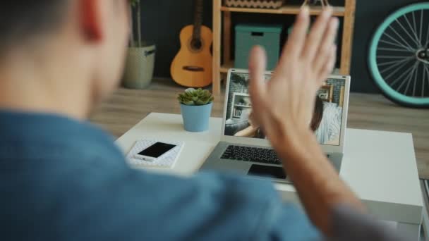 Чоловік робить онлайн відеодзвінок з ноутбуком, що розмовляє з жінкою та дитиною з дому — стокове відео