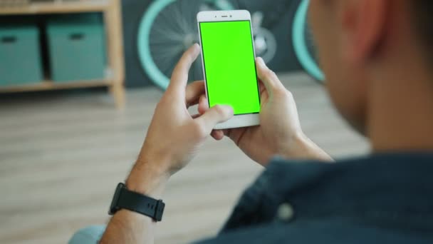 Чоловіча рука витирає смартфон із зеленим екраном, який торкається перегляду вмісту — стокове відео