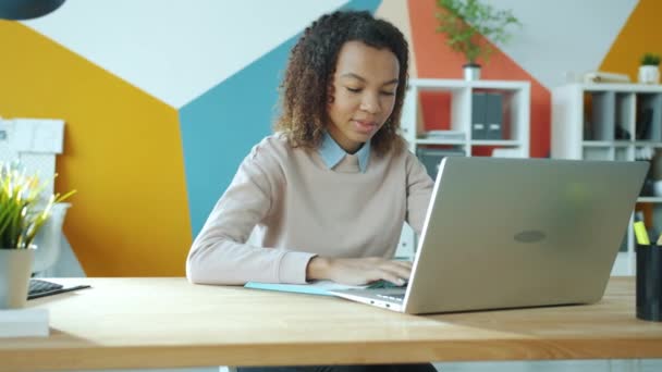 Портрет красивой афро-американской предпринимательницы, работающей с ноутбуком, улыбающейся печатая — стоковое видео