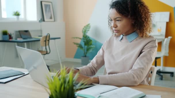 Uitgeput Afro-Amerikaanse vrouw is met behulp van laptop dan aanraken hoofd gevoel moe — Stockvideo