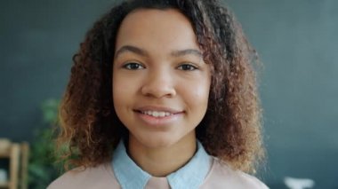 Çekici Afro-Amerikalı kadının yakın plan portresi. Evinde kameraya bakıyor.