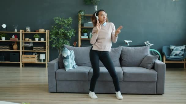 Kaygısız Afrikalı Amerikalı kadın evde dans edip şarkı söyleyerek eğleniyor. — Stok video