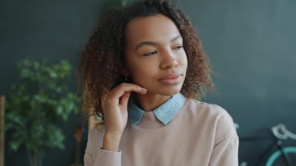 Retrato de una atractiva joven afroamericana sonriendo en el interior de su casa mirando a la cámara — Vídeos de Stock