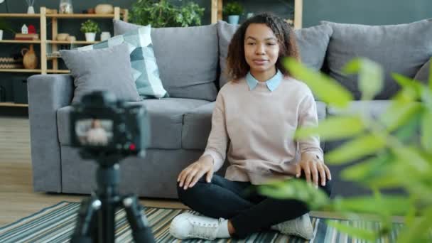 Joyful vlogger de raça mista gravação de vídeo em casa com câmera moderna mostrando gesto de polegar para cima — Vídeo de Stock