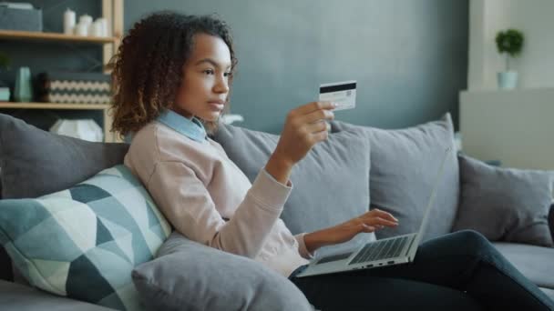Afro-americká žena provádět bezhotovostní platby on-line pomocí kreditní karty a notebooku psaní — Stock video
