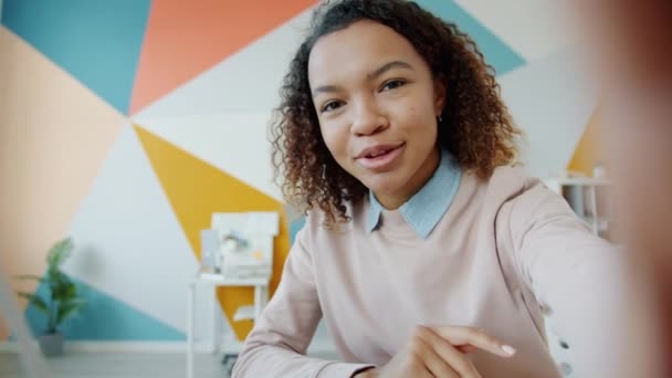 Porträtt av afro-amerikansk kvinna som ringer videosamtal från kontoret och viftar med handen — Stockvideo