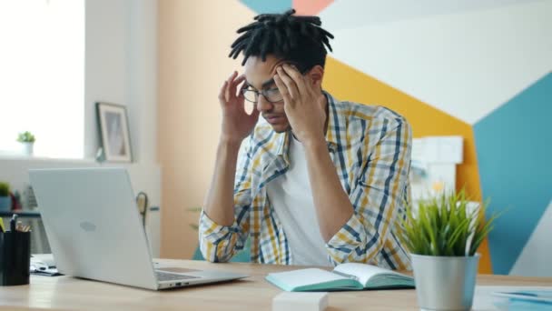 Épuisé mélange race homme se sentant mal de tête de travail avec ordinateur portable dans la salle de bureau — Video