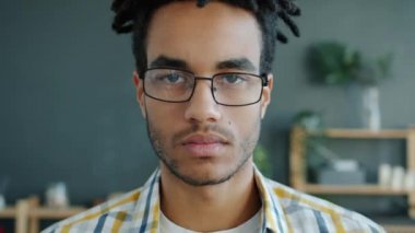 Ciddi bir Afro-Amerikan hipster 'ın yavaş çekim portresi. Evinde kameraya bakıyor.
