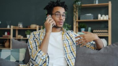 Neşeli Afro-Amerikalı öğrenci cep telefonuyla evde konuşuyor.