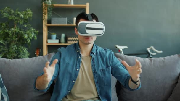 Câmera lenta de cara feliz desfrutando de óculos de realidade virtual em movimento braços no apartamento — Vídeo de Stock