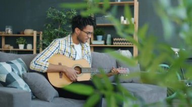 Evde gitar çalan genç Afro-Amerikalı adamın ağır çekimde