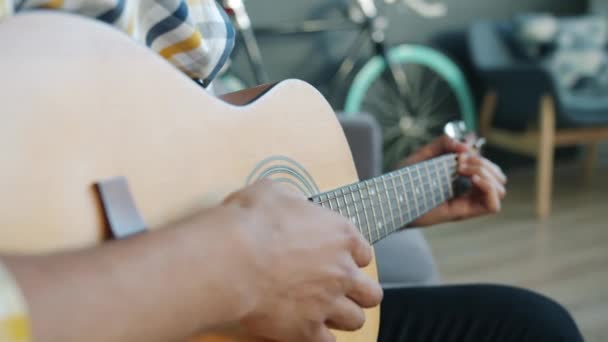 Gros plan de mains masculines jouant de la guitare à l'intérieur de la maison tenant un instrument de musique — Video