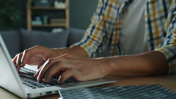 Повільний рух чоловічих рук, що друкують роботу з портативним комп'ютерним ноутбуком вдома — стокове відео