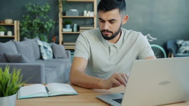 Movimento lento de morena bonita trabalhando com laptop tomando notas em casa — Vídeo de Stock