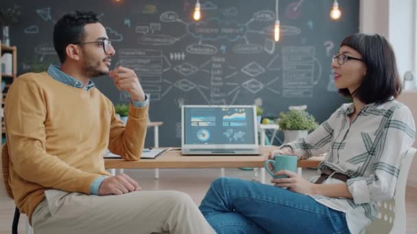 Boldog férfi és nő munkatársak beszélnek és nevetnek a modern közös irodában — Stock videók