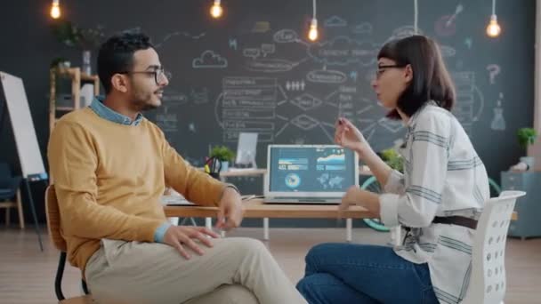 Biznesmeni mężczyzna i kobieta rozmawiają w biurze i za pomocą laptopa — Wideo stockowe