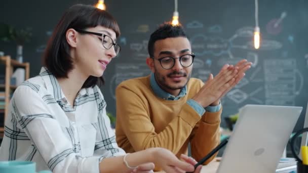 Mannelijke en vrouwelijke collega 's bespreken zakelijke ideeën in open ruimte kantoor met behulp van laptop — Stockvideo