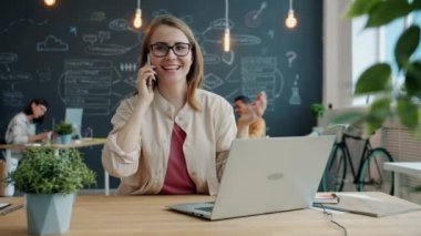 Ofiste cep telefonuyla konuşan genç iş kadını projeyi tartışıyor.