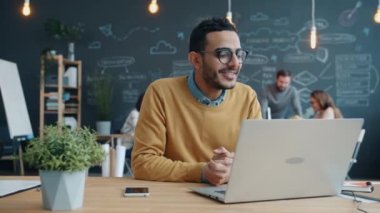 Mutlu Afro-Amerikalı iş adamının portresi iş yerinde bilgisayarla video görüşmesi yapıyor.