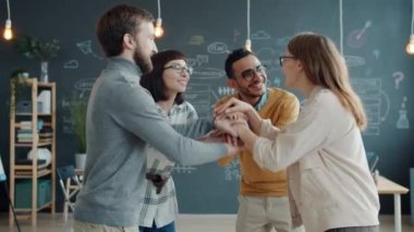 Bir grup genç el ele tutuşup gülüyor sonra da yaratıcı açık uzay ofisini alkışlıyor.