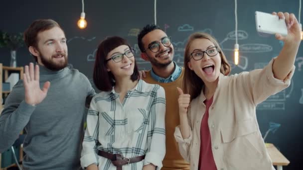 Skupina kolegů, kteří přebírají selfie v kanceláři pomocí kamery smartphone pózování s gesty rukou — Stock video