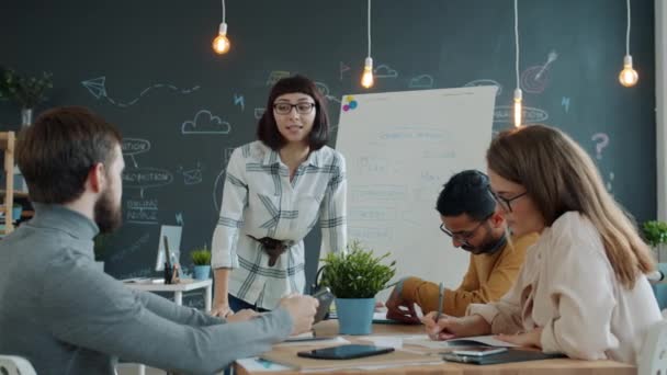 Jonge vrouw teamleider praten met collega 's schrijven op whiteboard in het kantoor — Stockvideo