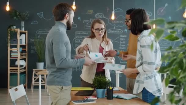 Colegas homens e mulheres compartilhando ideias de negócios olhando para papéis no escritório — Vídeo de Stock