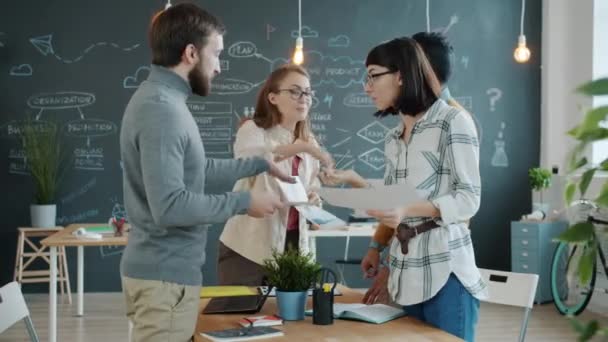 Colleagues men and women sharing business ideas looking at papers in office — Stock Video