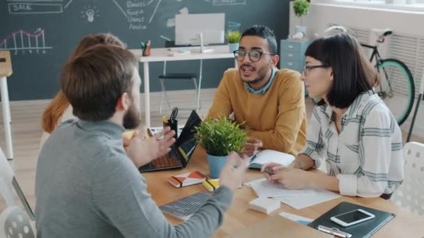 Мужчины и женщины-коллеги делятся идеями, работая вместе в офисе — стоковое видео