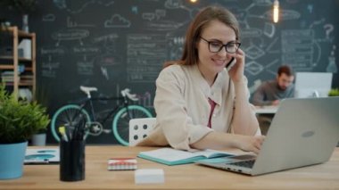 İş kadını telefonla konuşmakla ve dizüstü bilgisayarla çalışmakla meşgul.