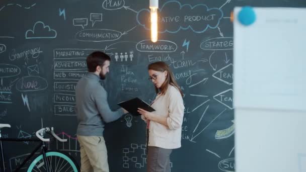 사업가들은 사무실에 분필을 가지고 작업을 논의하고 칠판 벽에 글씨를 쓰는 일을 의논 한다 — 비디오