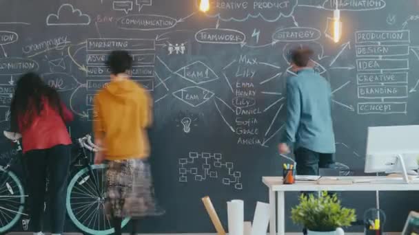 Zoom-out time lapse of people diverse group working together writing and drawing on blackboard — Wideo stockowe